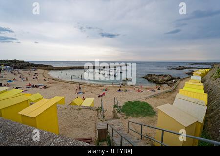 Le Croisic, France. 10 août 2025 : petits bateaux ancrés près de la plage de sable et des cabanes jaunes en bord de mer au Croisic sur la côte atlantique de la France Banque D'Images