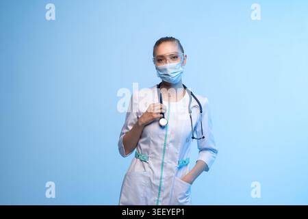 Travailleur médical debout, regardant la caméra, portant des équipements de protection et des gommages, symbolisant la santé et la protection Banque D'Images