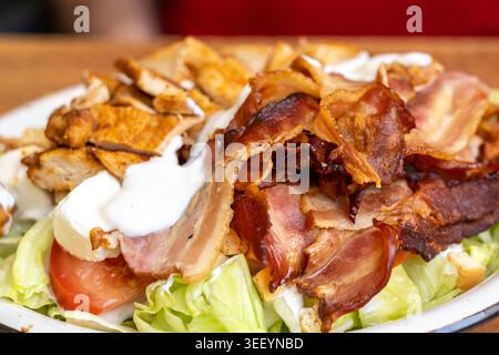 Salade César polonaise avec poulet, bacon et légumes garnie de vinaigrette en gros plan. Salade de viande riche en calories avec légumes frais, foo Europe de l'est Banque D'Images
