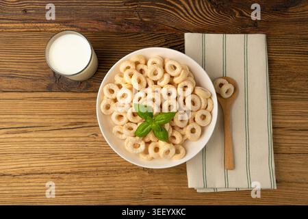 Anneaux de céréales sur la table en bois, boucles de riz de petit déjeuner, snack de céréales de maïs sur fond rustique Banque D'Images
