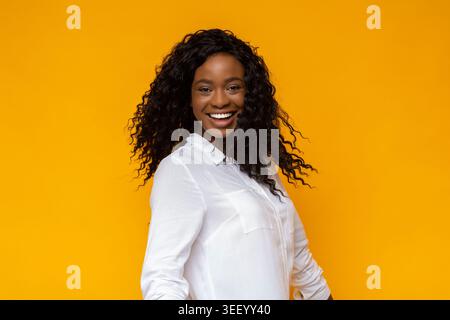 Femme souriant sur fond jaune vibrant en chemise blanche décontractée Banque D'Images