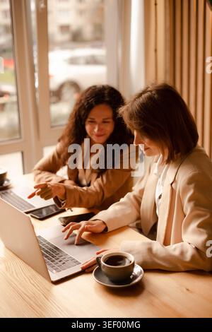 deux femmes d'affaires travaillant sur des ordinateurs portables et discutant du projet dans un café Banque D'Images