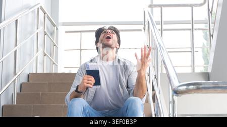 Vol Perdu. Homme Désespéré Assis À L'Aéroport Avec Passeport Banque D'Images