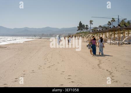 Les gens marchant le long de la large plage de sable pendant les vacances d'été Banque D'Images