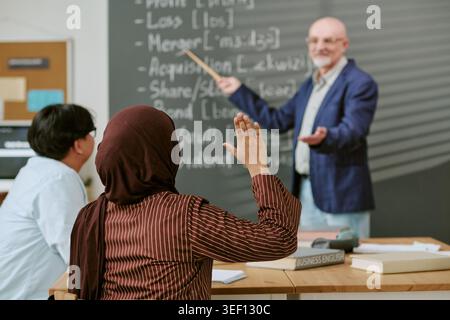 Femme migrante levant la main pendant le cours d'anglais des affaires Banque D'Images