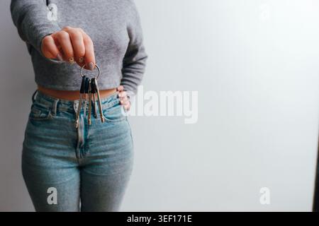 Une femme attrayante en jeans et un haut tient un tas de clés dans sa main. Concept de style de vie des gens. copier l'espace. Tenez la maison bouquet de clés, pointant Banque D'Images