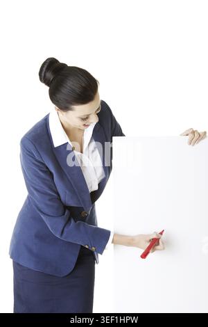 Femme d'affaires attrayante tenant un tableau blanc et écrivant dessus avec marqueur. Isolé sur blanc Banque D'Images