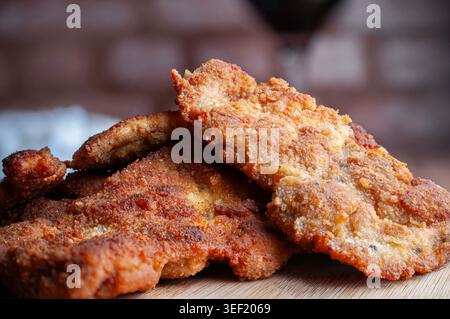 Poulet pané, poisson, crevettes ou escalopes de bœuf, avec nouilles ou fettuccine et fourchette sur le côté, vue de côté avec escalopes panées en arrière-plan Banque D'Images