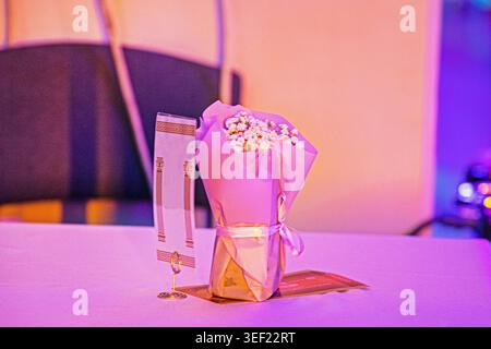 Un bouquet de lis de la vallée enveloppé dans du papier sur une table avec un éclairage festif Banque D'Images