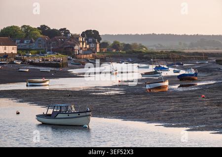 Petits bateaux amarrés dans le canal de l'estuaire boueux à marée basse à Burnham Overy Staithe, Norfolk, Angleterre Banque D'Images