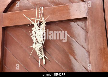 Décoration traditionnelle du dimanche des Rameaux accrochée à une porte en bois rustique, symbolisant la foi chrétienne, la célébration de la semaine Sainte et la culture religieuse. Banque D'Images