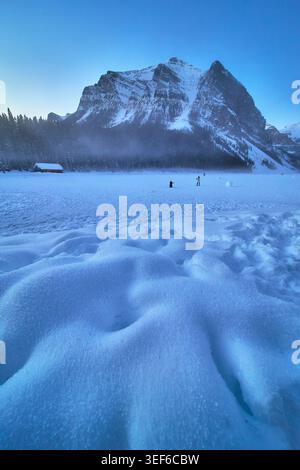 Paysage hivernal du lac gelé avec la montagne enneigée et les gens de Banff, Alberta Banque D'Images