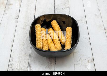 les lanières de poulet, avec leur couleur brun doré caractéristique, sont servies sur un lit de frites jaunes et à côté d'une portion de purée de pois vert vif. Banque D'Images