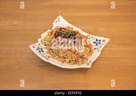 Une vue plongeante capture du riz frit indonésien (nasi goreng) couronné d'un œuf frit aux bords croustillants, accompagné de brochettes de poulet satay, tranchées de ​​c Banque D'Images