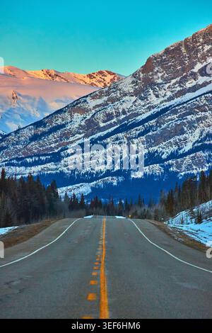 Winter Sunrise Road et Snowy Mountains avec Forest en Alberta Banque D'Images