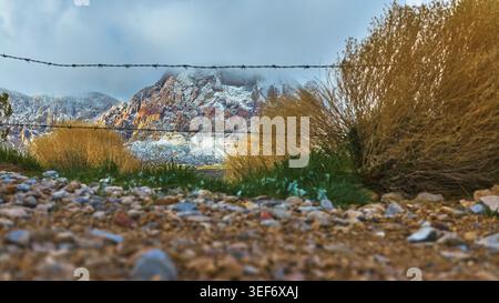 Montagnes Red Rock enneigées au rez-de-chaussée avec gravier du désert et clôture en fil de fer barbelé Banque D'Images