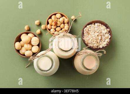 Composition avec des bouteilles de lait végétalien différent sur fond vert Banque D'Images