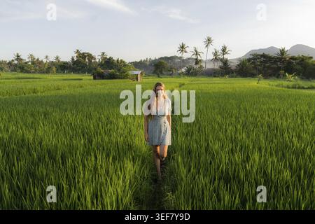 Femme marchant dans un champ de riz au lever du soleil, Mont Agung, Bali, Indonésie Banque D'Images