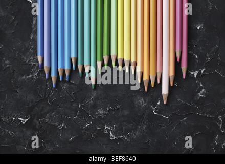 Beaux crayons de couleur pour dessiner sur fond de plâtre noir. Vue de dessus. Pose à plat Banque D'Images