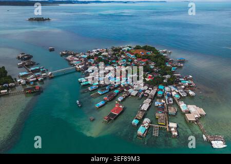 Vue aérienne d'un village traditionnel sur pilotis avec des toits colorés entourés d'eaux turquoises et de verdure luxuriante Kepulauan Riau, Indonésie. Banque D'Images