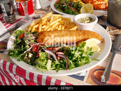 Le mélange de salade verte fraîche sert de plat d'accompagnement coloré sain pour le poisson frit doré. Feuilles de laitue croquantes mélangées avec du chou violet et mûres Banque D'Images