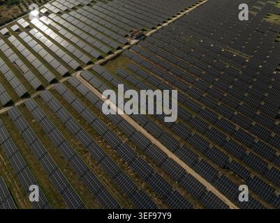 Vue aérienne d'une vaste ferme de panneaux solaires avec des rangées de modules photovoltaïques réfléchissant la lumière du soleil à Priolo Gargallo, Sicile, Italie. Banque D'Images