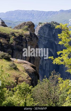 spectaculaires piliers de grès des météores s'élèvent au-dessus d'un feuillage vert luxuriant sous un ciel clair, capturant l'ancienne majesté géologique de ce grec unesco l Banque D'Images