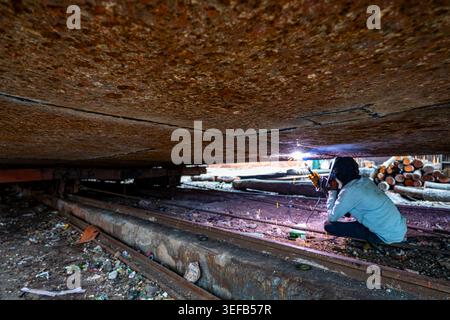 Des hommes réparent un bateau dans un chantier de naufrage alors qu’ils travaillent avec du matériel de soudage à Dhaka, au Bangladesh Banque D'Images