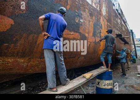Des hommes travaillent à réparer un bateau dans un chantier naval à Dhaka tout en montrant des compétences en restauration de bateaux au Bangladesh Banque D'Images