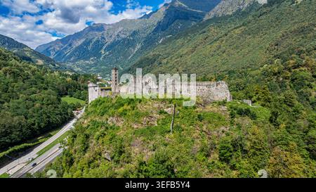 Vue du château de Mesocco sur une colline entourée de montagnes et de verdure en Suisse sous un ciel nuageux Banque D'Images