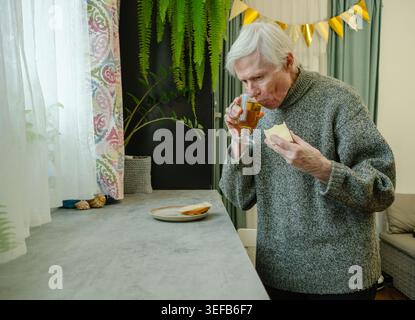 Une personne âgée prépare et mange son propre petit-déjeuner, mettant en évidence l'indépendance et l'autonomie dans la vieillesse. L'image montre la capacité et la routine. Grand-père gérant son propre repas. Banque D'Images