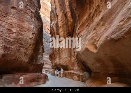 Les visiteurs traversent le Siq, une gorge étroite qui mène à un site archéologique en Jordanie Banque D'Images