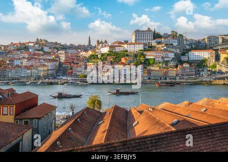 Vue de Porto Ribeira, Portugal, à travers le fleuve Douro sur les toits de maisons, avec des bateaux rabelo touristiques sur le fleuve Douro et des toits rouges dans le Forward Banque D'Images