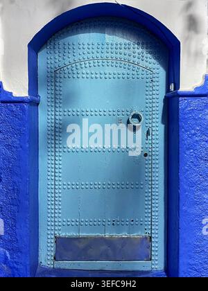 Une porte bleue vibrante et une ruelle décorée artisanalement et les murs indigo emblématiques de la « ville bleue » – Chefchaouen, Maroc. 5 août 2025 Banque D'Images