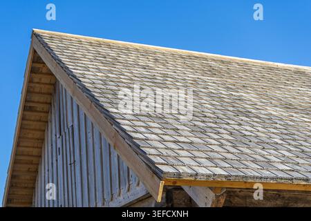 Toiture traditionnelle en bardeaux de bois d'une ancienne grange contre un ciel bleu clair Banque D'Images