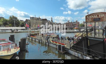 Canal avec des bateaux et des bâtiments historiques sous un ciel ensoleillé à Amsterdam, pays-Bas. Banque D'Images
