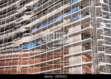 Un échafaudage métallique enveloppe un nouveau bâtiment en béton, mettant en évidence les techniques architecturales innovantes en cours. Banque D'Images