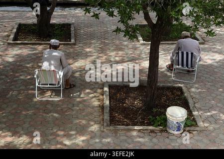 Hommes omanais assis dans la place sous fiscus Tree Falaj Al-Khatmeen Birkat Al Mouz Sultanat d'Oman Banque D'Images