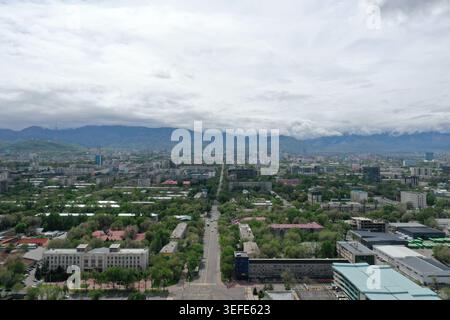 Une vue aérienne étendue capture une ville moderne tentaculaire nichée au milieu d'une végétation luxuriante avec des bâtiments imposants s'étendant vers la montagne brumeuse R. Banque D'Images