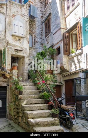 Pittoresque ruelle étroite dans la vieille ville de Rovinj avec des escaliers en pierre, des plantes en pot et un scooter stationné en Istrie Croatie Banque D'Images