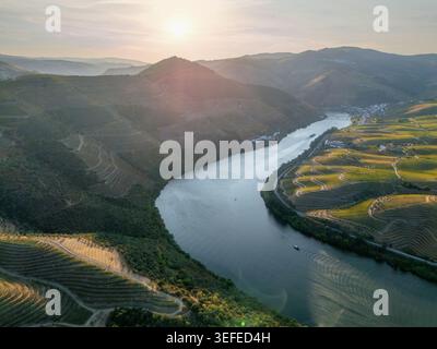 Vue aérienne par drone du fleuve Douro serpentant entre les collines de vignobles dans la vallée du Douro, Portugal, avec lumière douce du coucher du soleil. Banque D'Images