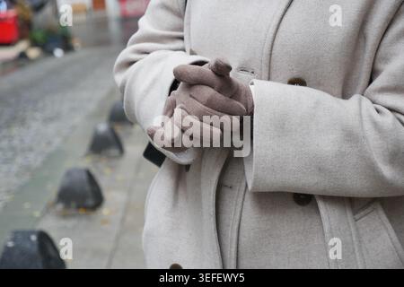 Femme en manteau gris tient les mains ensemble par temps frais Banque D'Images