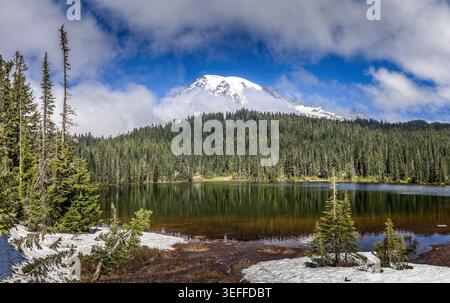 Couvert de neige Mont Rainier reflétant dans un lac alpin calme entouré de forêt à feuilles persistantes sous un ciel bleu vif Banque D'Images