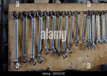 Gros plan de plusieurs clés métalliques soigneusement disposées sur un mur en bois à l'intérieur d'un atelier, montrant les outils, l'artisanat et l'environnement de travail organisé wi Banque D'Images