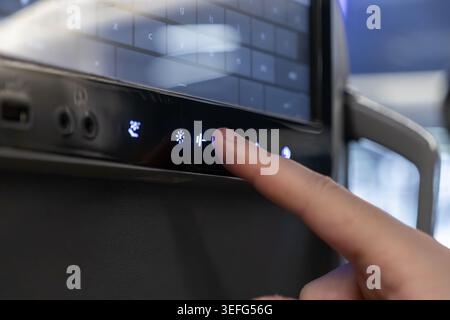 Gros plan d'une main activant une icône de commande de siège d'avion sur un écran tactile, mettant l'accent sur l'infrastructure de voyage innovante, le passager comfor Banque D'Images