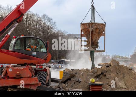 Varsovie, Pologne - 13 avril 2026 : une grue rouge fonctionne avec un seau lourd pour couler du béton sur un chantier de construction urbaine, mettant en vedette l'industrie lourde, civile Banque D'Images