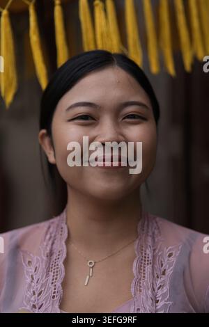 Jeune femme balinaise en kebaya rose souriante, Bali, Indonésie Banque D'Images