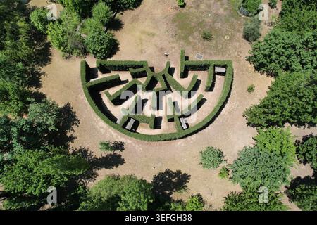 Vue aérienne d'un labyrinthe de haies semi-circulaire entouré d'arbres verts et d'herbe sèche à Turin, Piémont, Italie. Banque D'Images