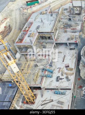 Vue aérienne d'un grand chantier de construction avec des fondations en béton, un échafaudage et une grue à tour jaune à Avcilar, Istanbul, Turkiye. Banque D'Images
