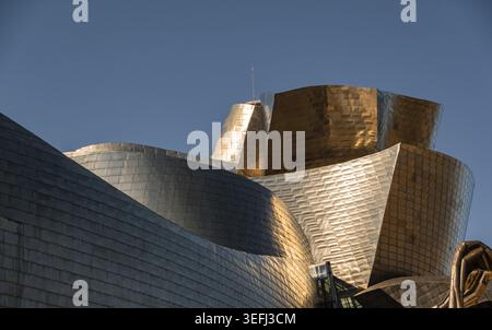 Vue sur les courbes chatoyantes en titane et l'architecture métallique du Musée Guggenheim Bilbao sous un ciel bleu clair à Bilbao, Euskadi, Espagne. Banque D'Images